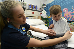 A young female nurse treats a young boy in the emergency department
