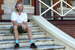 A man sits on steps leading to a verandah