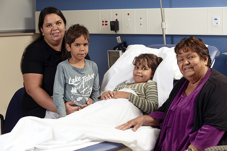 A young Aboriginal girl surrounded by family members