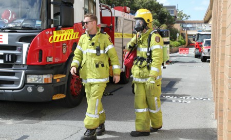 Two fire fighters standing beside a fire engine