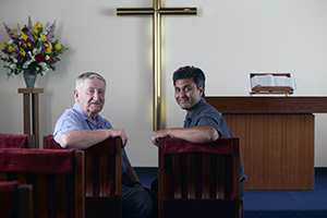 Two men seated in a chapel.